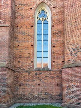 Brick facade with gothic window in medieval church Foto stock