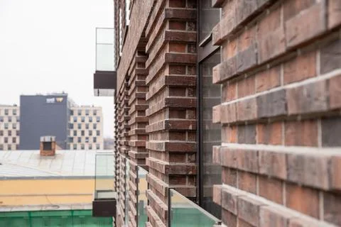 Brick facade with projecting masonry and windows overlooks a rooftop. Repea.. Foto stock