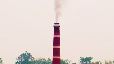 A brick factory chimney stack billows smoke polluting the sky over Video stock 242080808