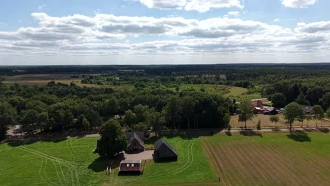 Brick farmhouse cluster with dark timber barns sits amid vast mowed grass Stock Footage 346005735