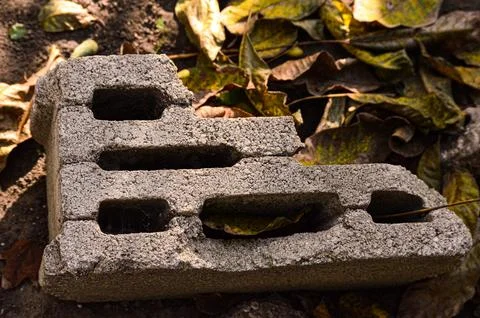A brick with a hole in it is sitting on the ground Foto stock