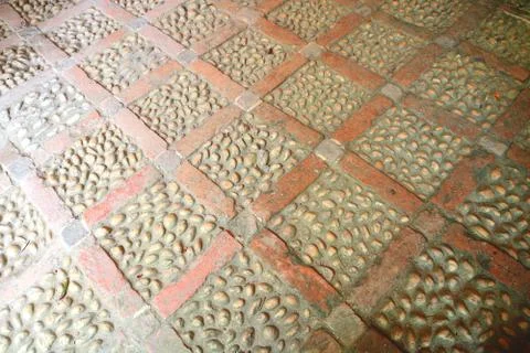 A brick laid floor in a diamond pattern inlaid with beach pebbles. Stock Photos