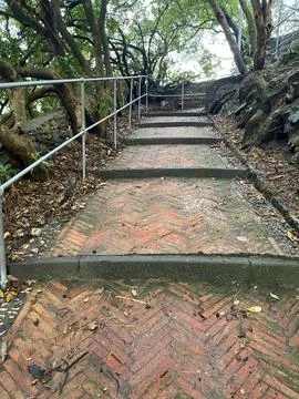 Brick old steps on path up hill amongst trees. Ancient building. Traditional Stock Photos