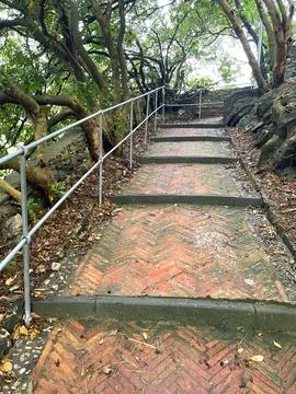 Brick old steps on path up hill amongst trees. Ancient building. Traditional Stock Photos