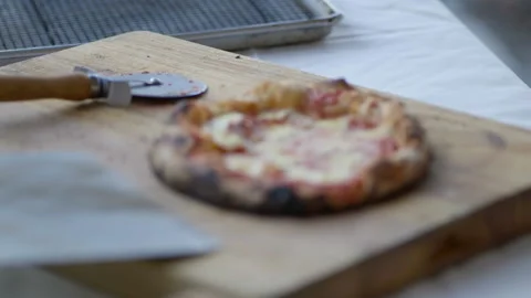 Brick oven pizza being placed on cutting board slow Stock Footage 170374504