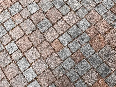 A brick patterned floor with a mix of gray and brown tiles Stock Photos