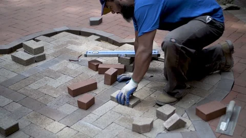 Brick paver artisan fitting a brick into the herringbone two-tone pattern and Stock Footage 80513864
