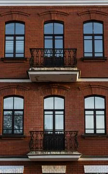 Brick, red facade of an old building with balconies Stock Photos