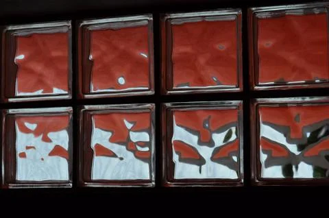 Brick red wall glows behind glass window Stock-Fotos