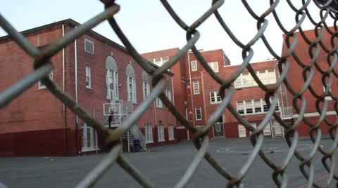 Brick School and Blacktop Behind Wire Fence Dolly Out Video stock 24262448