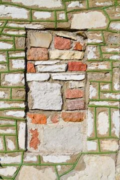 Brick side of a building with moss growing in the cracks with a red square where Stockfoto's