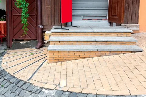 Brick threshold on the slope with granite steps to the open wooden entrance. Stock Photos