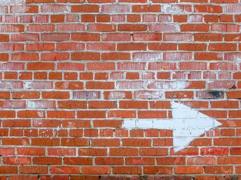 Brick wall with an arrow pointing in the direction Stock Photos