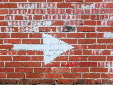 Brick wall with an arrow pointing in the direction Stock Photos