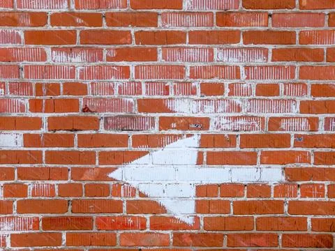 Brick wall with an arrow pointing in the direction Stock Photos