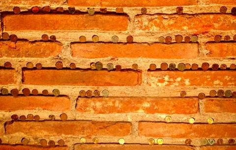 Brick wall background with coins on the bricks Stock Photos