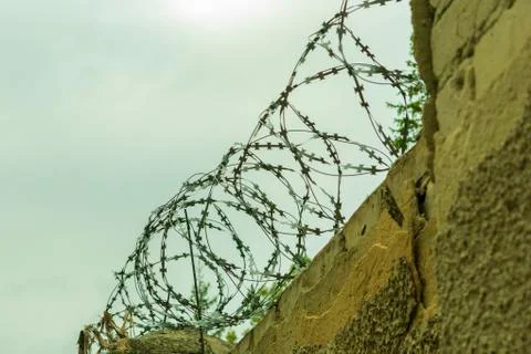 Brick wall with barbed wire, close-up against the sky Stock Photos