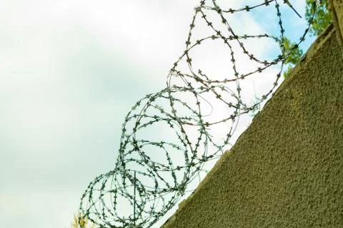 Brick wall with barbed wire, close-up against the sky Foto stock