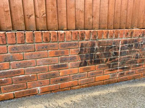 Brick wall being cleaned. Dirt and grime can be seen on the part which has no Stock Photos