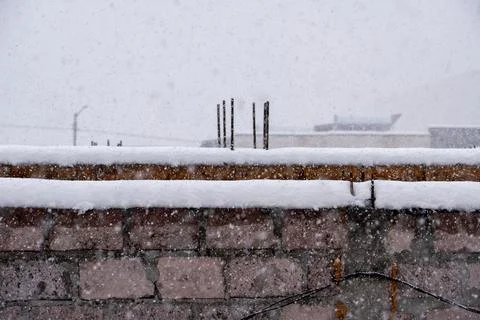 Brick wall of building under construction during heavy winter snowfall. Stock Photos