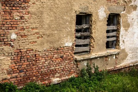 A brick wall constructed with several windows that are currently boarded up Stock Photos