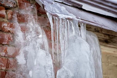 A brick wall covered in ice. icicles on the roof Stock Photos