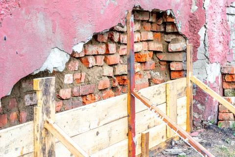 A brick wall is destroyed due to high humidity and low-quality materials used Stock Photos
