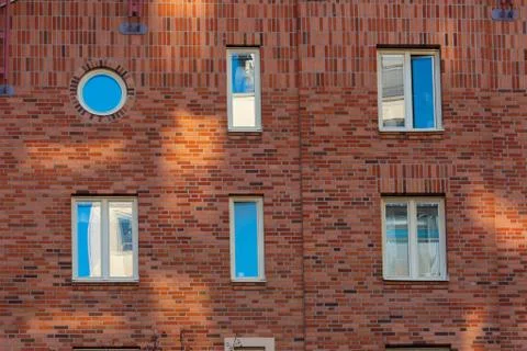 Brick wall with five square windows and one round. Stock Photos