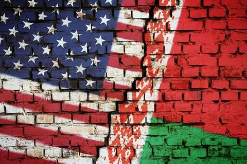 Brick wall with a flag of Belarus and the USA with a big crack in the middle Stock Photos