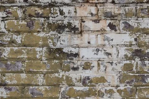 Brick wall with layers of grey, white, and green peeling paint Stock Photos