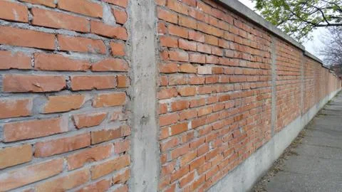 Brick wall made of bright red bricks around a catholic cemetery. The fence is Stock Photos