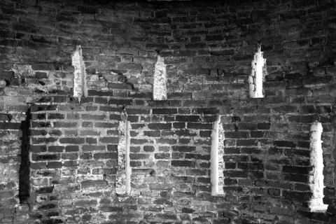 Brick wall with openings in the form of windows in black and white. Stock Photos