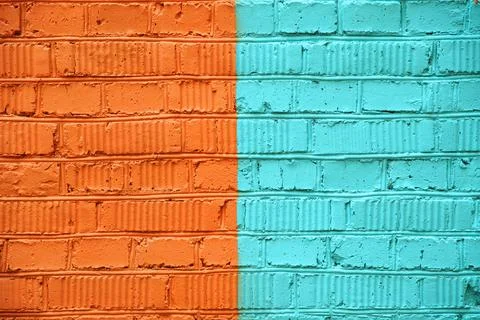 Brick wall, painted half orange and turquoise paint, with real cracks and den Stock Photos