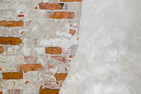 The brick wall is partially cleared from plaster to the basis of red bricks. Stock Photos