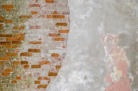 The brick wall is partially cleared from plaster to the basis of red bricks. Stock Photos