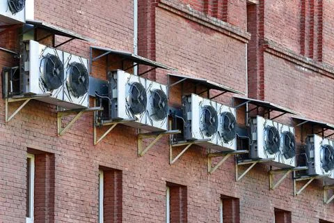 Brick wall with a range of large air conditioners Stock Photos