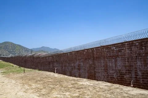 Brick wall with razor wire, correctional facility, prison wall, mountains Stock Photos