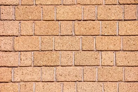 A brick wall with a rough texture and a light brown color Stock Photos