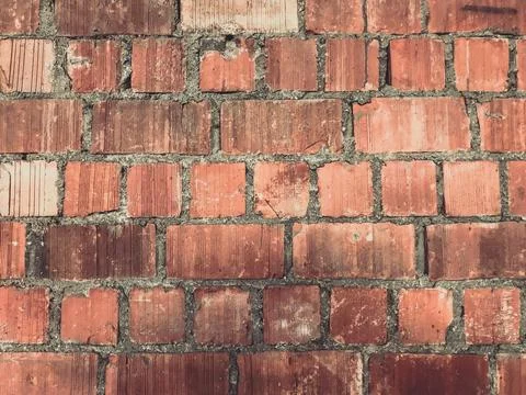 A brick wall with a rough texture and a faded red color Stock Photos