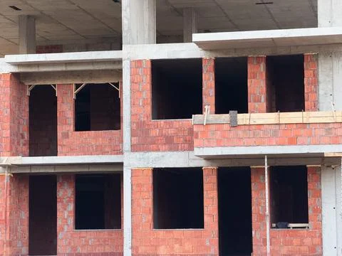 Brick wall sections with window openings in unfinished apartment building fac Stock Photos
