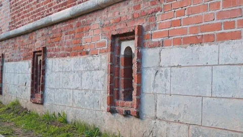 Brick wall with several small window openings at ground level. This setting Vídeos de archivo 344528020