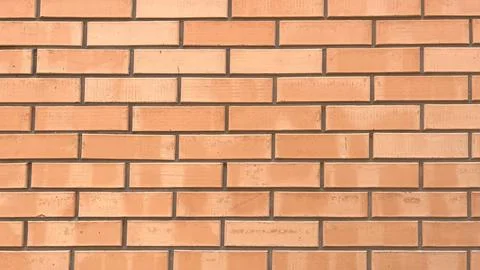 Brick wall showcasing a pattern of rectangular bricks in warm orange tones .. Stock Photos