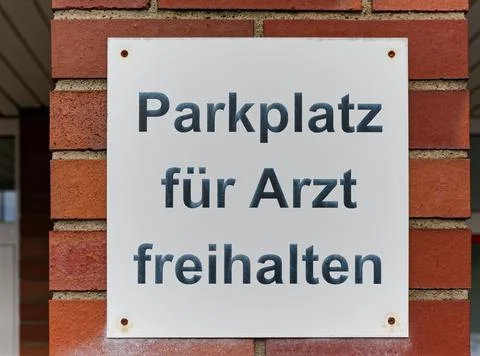 Brick wall sign says keep parking space free for doctor. Stock Photos