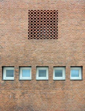 Brick wall with small windows and a decorative lattice Foto stock