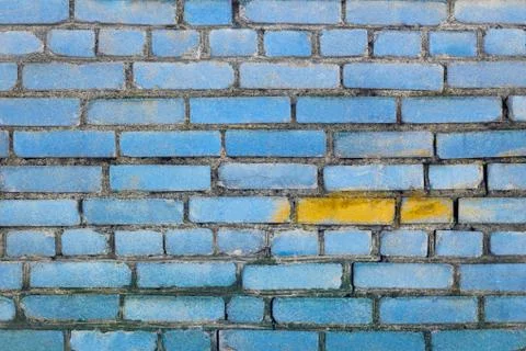 Brick wall texture painted blue with yellow spot Stock Photos