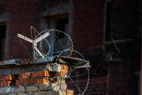 A brick wall is topped with barbed wire for security. Foto stock