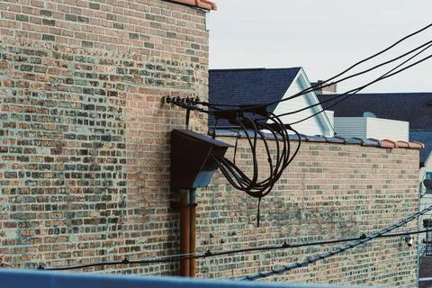 Brick wall with utility cables attached in a city during the evening hours .. Stock Photos