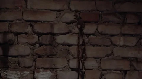 A brick wall on which hangs an old chain and an iron hook Stock Footage 247019333