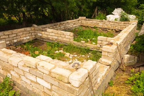 Brick wall of white bricks at an early stage of construction. Foundation Stock Photos