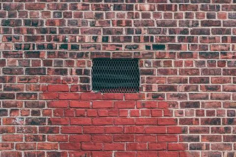 A brick wall with a window in the middle Stock Photos